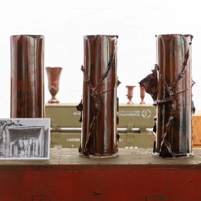gallery view of brown red ceramics on top of stacks of ammunition boxes